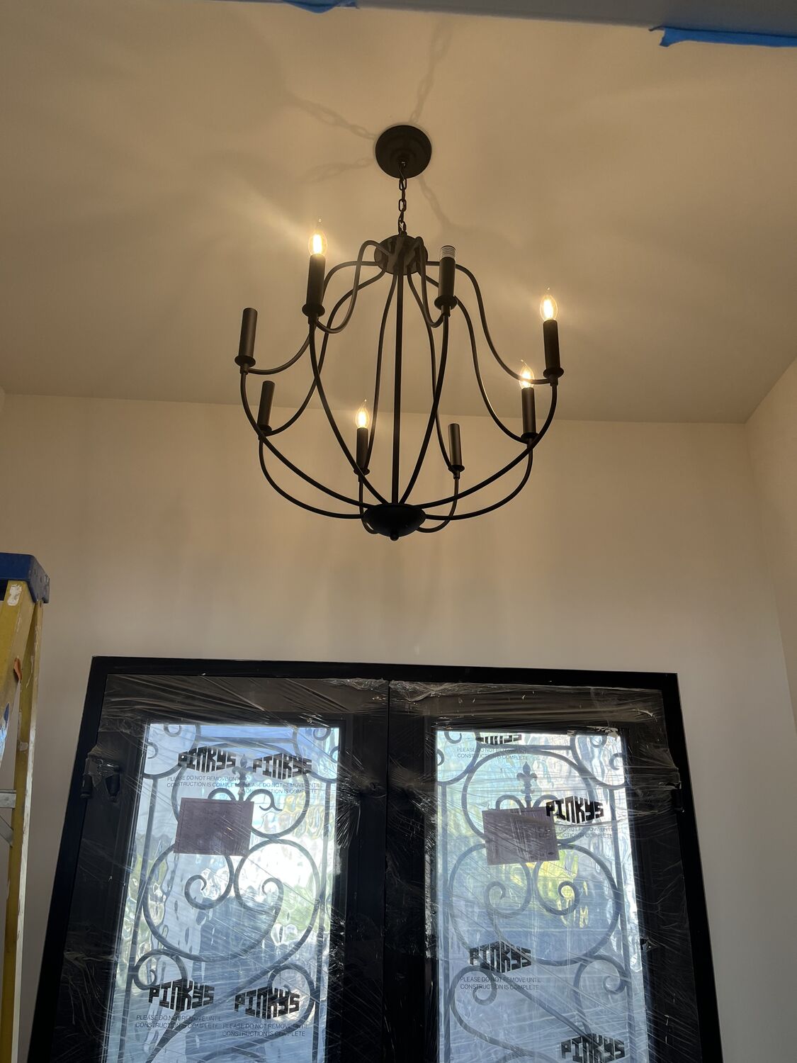 Wrought-iron chandelier installed over a foyer entry by All Current Electric