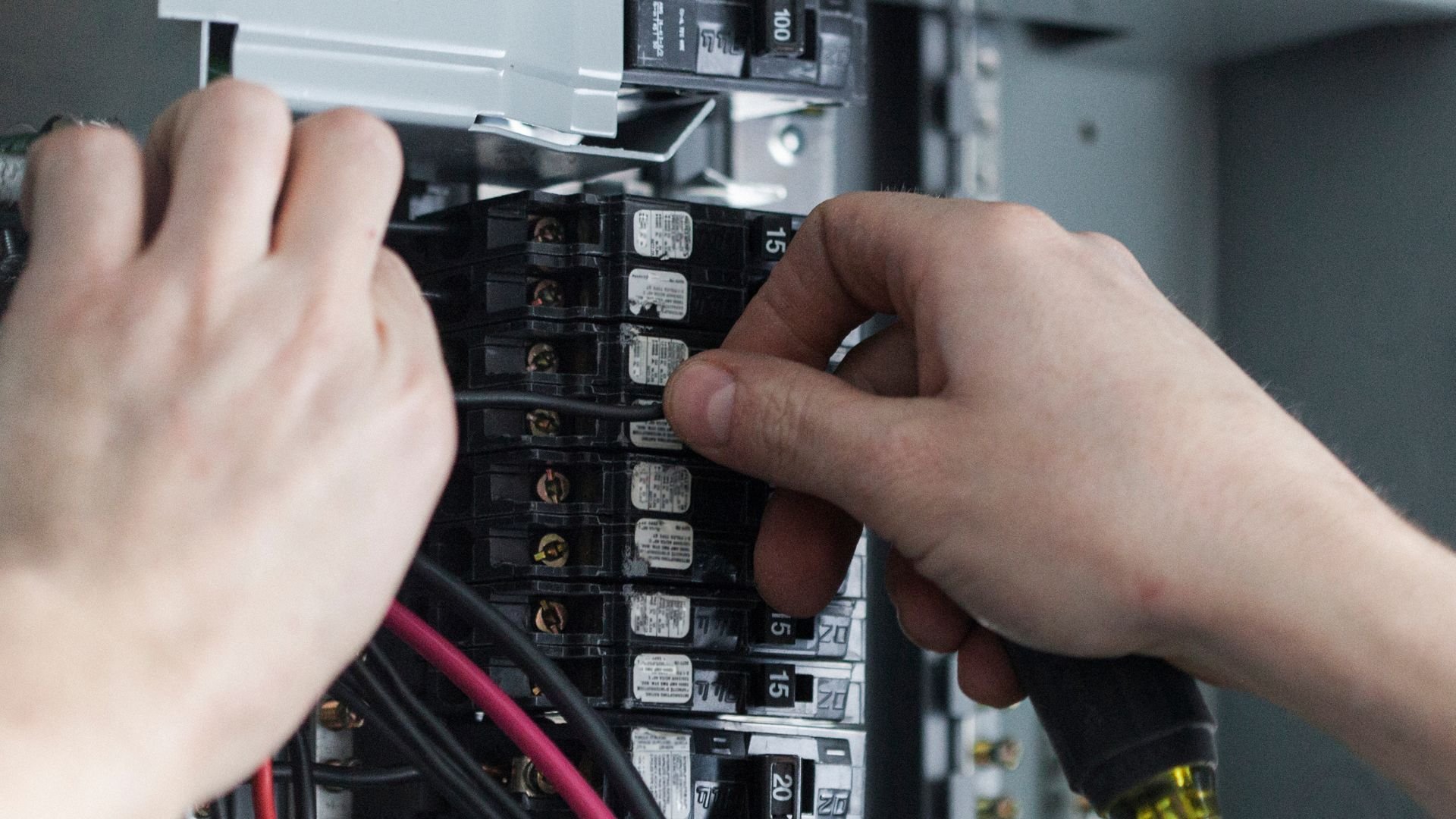 Hands adjusting electrical circuit breakers in an industrial electrical panel