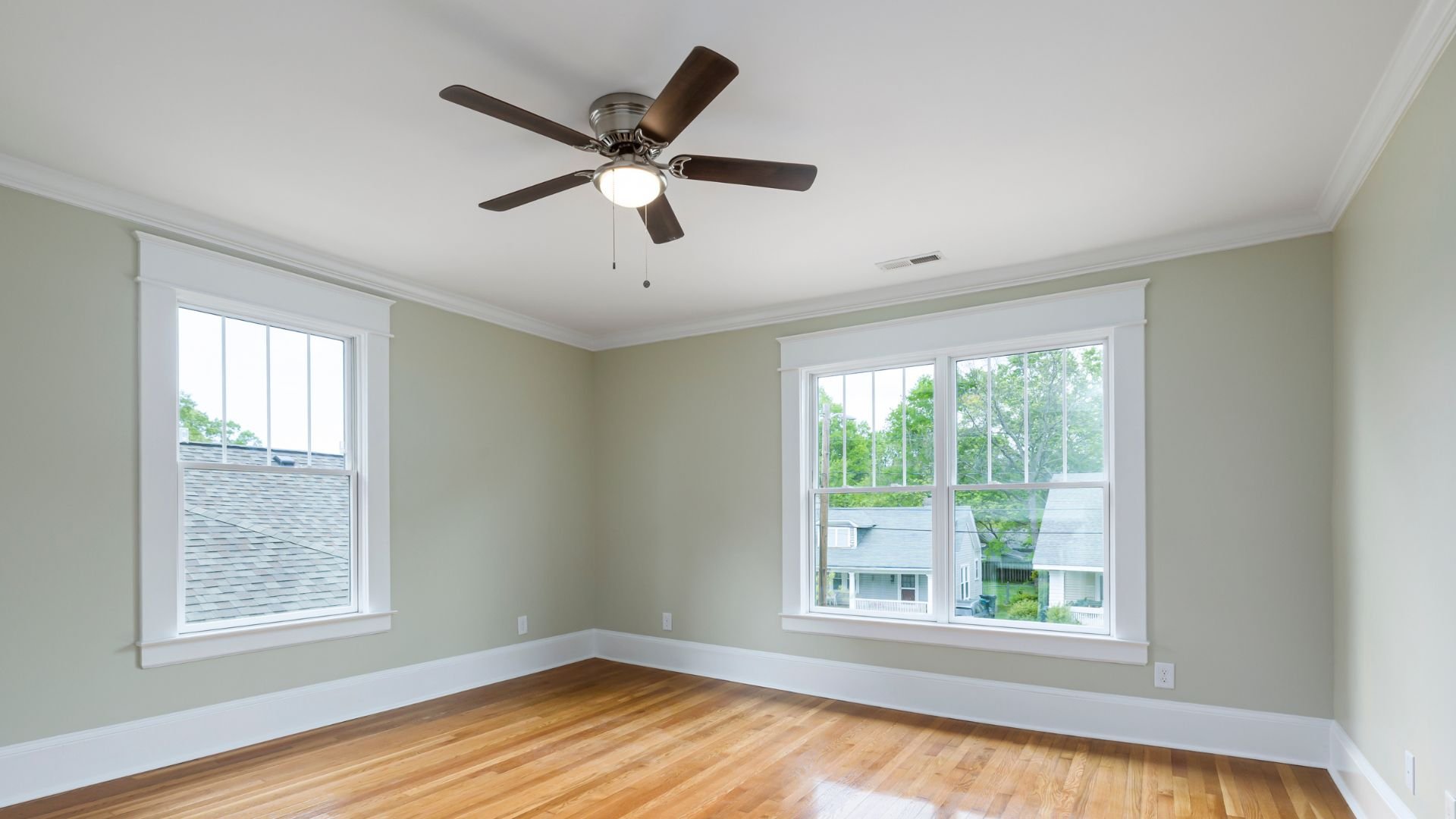 Empty room with hardwood floor, windows, and ceiling fan